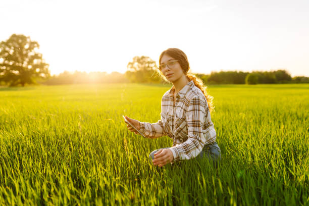 istock Young Woman Farmer on a green wheat field with a tablet in his hands. 2149356021