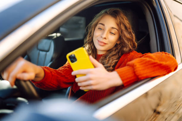 istock Young woman is driving a car with phone. 2149357642