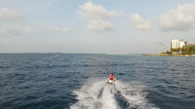 Young Couple Riding Jet Ski on Maldives Island Vacation, Drone Tracking Shot
