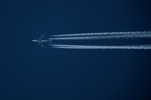 Airplane in the blue sky with contrails of the plane.