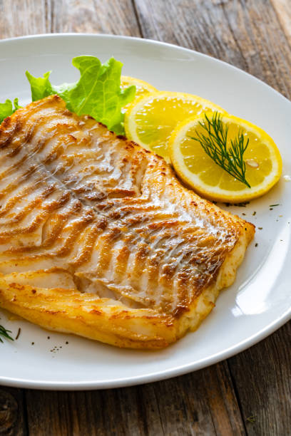 istock Fried cod fillet and fresh vegetables on wooden table 2149358451