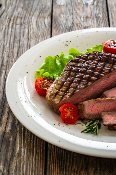istock Grilled beef sirloin steak with fresh vegetables on wooden table 2149358519