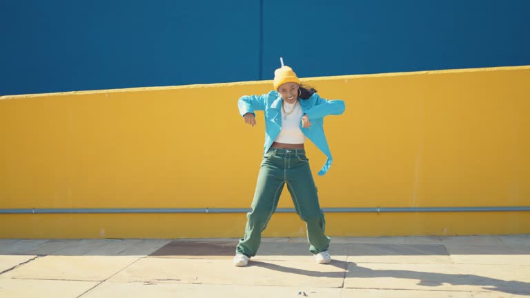 Teenager girl with fashionable clothes dancing in a colored modern area of the city