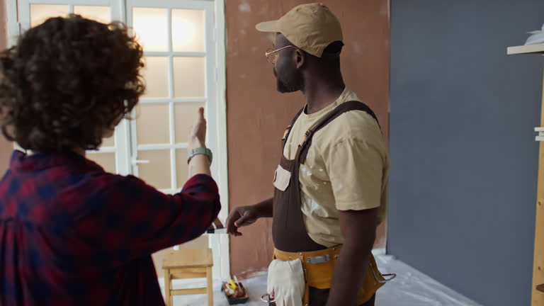 Lady Talking to Handyman Choosing Wall Color in Renovating Room