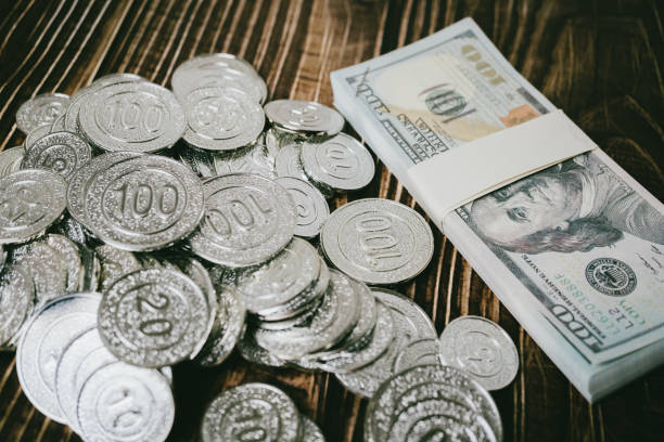 Stacks of silver coins on a white surface, with some stacks blurred in the foreground and one stack in focus.