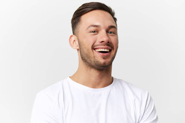 istock Joyful cute happy young tanned handsome man in basic t-shirt laugh at camera posing isolated on over white studio background. Copy space Banner Mockup. People emotions Lifestyle concept. Portrait 2149361461