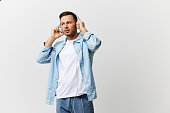 Young serious tanned handsome man in casual basic t-shirt touch wear headphones listen fav playlist posing isolated on over white studio background. Copy space Banner Mockup. Cool playlist concept
