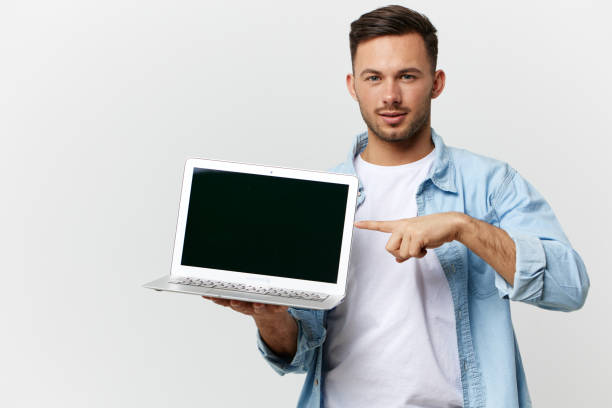 istock Serious friendly tanned handsome IT professional man in casual basic t-shirt point finger at laptop posing isolated on white studio background. Copy space Banner Mockup. Electronics repair concept 2149362044