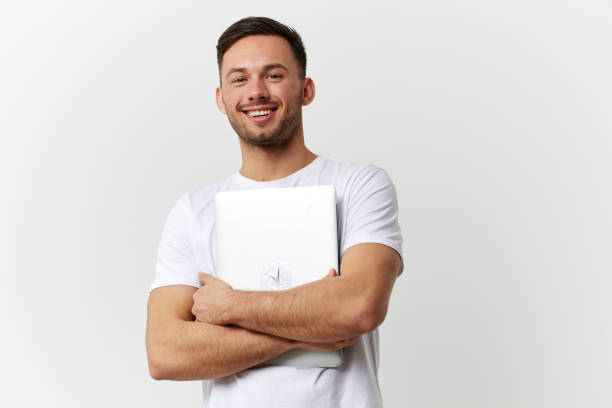 istock Cheerful happy tanned handsome man in basic t-shirt hugging with laptop pc posing isolated on over white studio background. Copy space Banner Mockup. Electronics repair Gadget lifestyle concept 2149362456