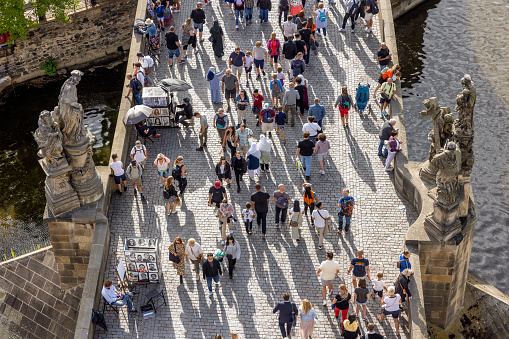 Prague, Czech Republic - July 26, 2024: People walking over cobblestone pedestrian Charles Bridge Karluv Most over Vltava river