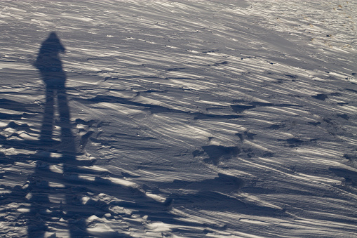 Elongated man shadow in the snow at high altitude, self portrait of mountaineer