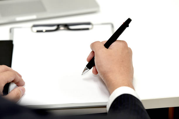 Hand of a businessman in a suit writing documents