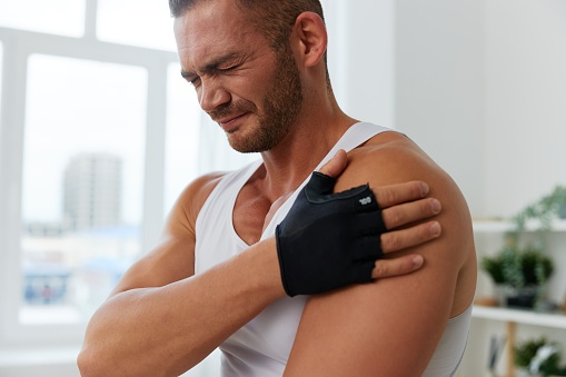 Man sports arm pain muscle and ligament sprain from working out at home, pumped up man fitness trainer works out at home, the concept of health and body beauty. High quality photo