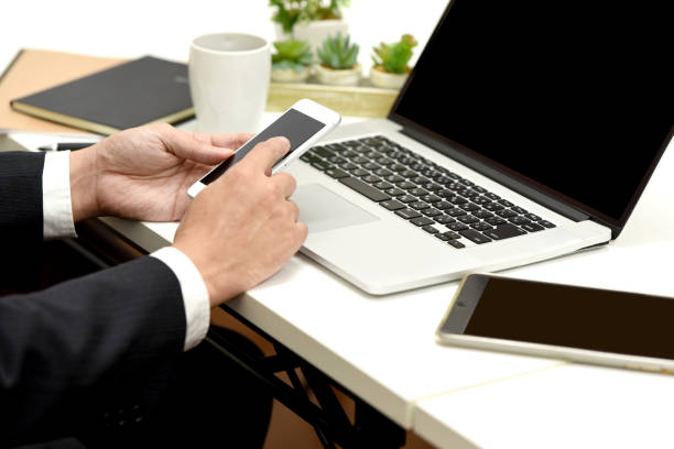 istock Businessman's hand operating a smartphone in front of a laptop 2149366302