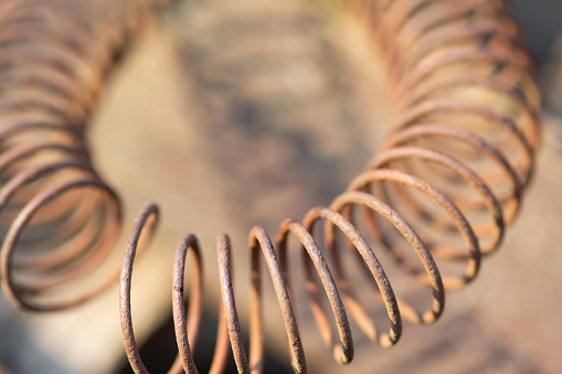 Old metal spring or iron spiral, close-up photo. Shallow depth of field, blurred background.