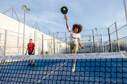 Diverse Couple playing paddle tennis in court
