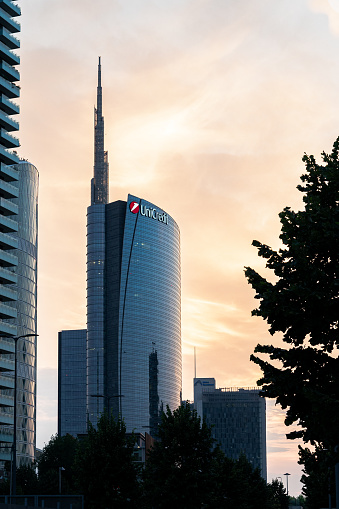 Milan, Lombardy, Italy- June 27, 2023; The majestic Unicredit Tower rises imposingly on the skyline of Milan, Italy. At 231 meters tall, it dominates the cityscape, making it the tallest building in the country. Part of the ambitious Porta Nuova project, the skyscraper is the epitome of modernity and sustainability. Designed by renowned architect César Pelli, it is part of a complex of residential and office buildings that revitalize a vast area of 290,000 m². The Unicredit Tower stands as a symbol of energy efficiency, with a design that reduces energy consumption by an impressive 37%. Its glass and steel structure reflects innovation and commitment to a more sustainable future, while its imposing presence embodies the avant-garde spirit of Milan as Italy's economic and cultural center.