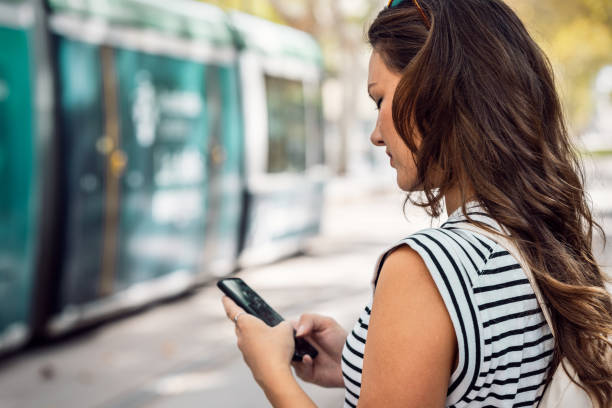 istock Confident woman using her mobile phone while waiting for the tram at the station 2149368665