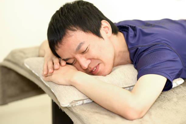 Chiropractor massaging the back and shoulders of an Asian man