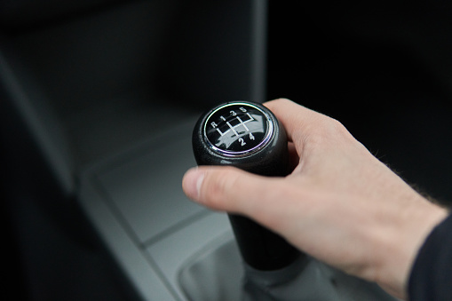 Man holding Manual gearbox transmission gear shifter knob handle stick shift in the car interior