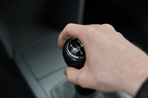 Man holding Manual gearbox transmission gear shifter knob handle stick shift in the car interior
