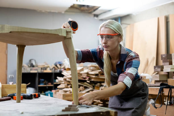 istock young carpenter women using measuring tape looking wood size at workspace. craftsman profession in wood factory. 2149374903