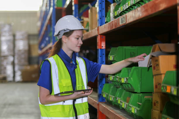 istock Female worker wearing safety uniform and hard hat using digital tablet checking inspect goods on shelves in warehouse. women worker check stock inspecting product in factory. 2149376957