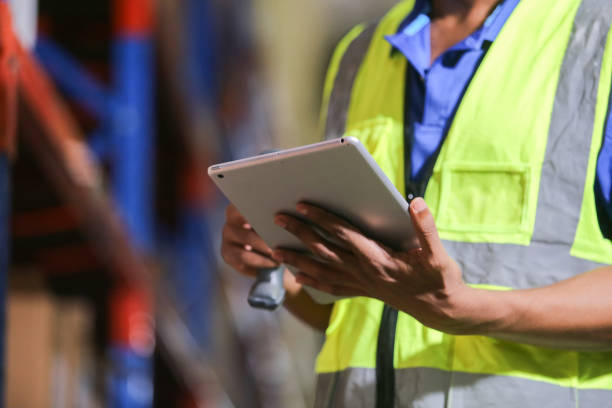 istock Close up Tablet, Man professional worker wearing safety uniform and hard hat using digital tablet inspect product on shelves in warehouse. Male worker check stock inspecting in storage logistic factory. 2149376975