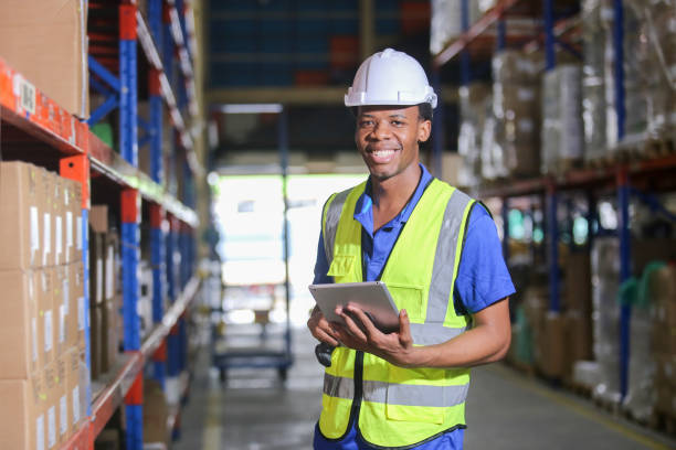 istock Portrait man american african professional worker wearing safety uniform using digital tablet inspect product on shelves in warehouse. Worker check stock inspecting in storage logistic factory. 2149376980