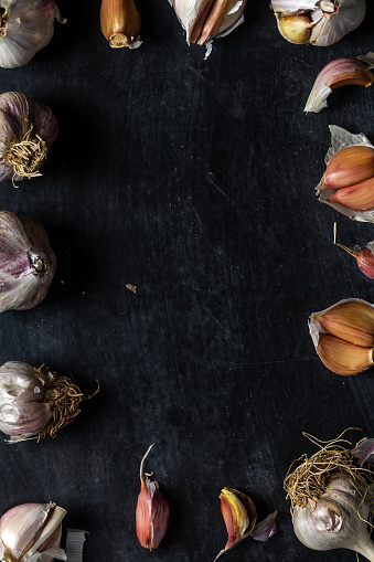 Fresh garlic bulbs and cloves grouped on black background. Flat lay. Top view. Food concept. Dark mood food photography.