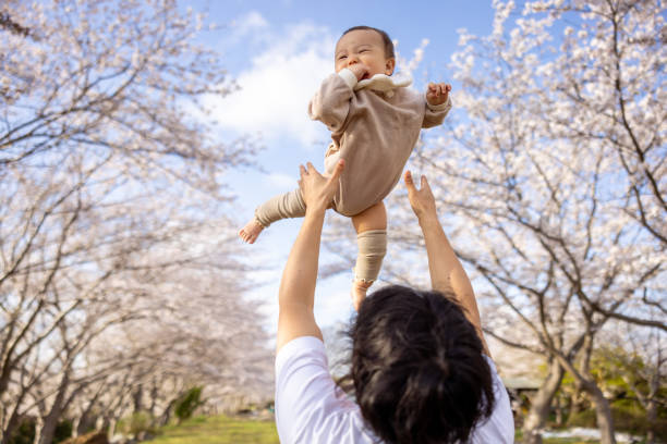 istock Father holding up his baby under cherry blossoms 2149380565