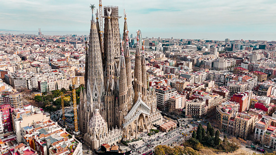 Aerial view of Sagrada Familia Cathedral in Barcelona, Catalonia, Spain, Aerial view of Barcelona Eixample residential area and Sagrada Familia Basilica, most famous travel destinations in europe

The Basílica i Temple Expiatori de la Sagrada Família, otherwise known as Sagrada Família, is a church under construction in the Eixample district of Barcelona, Catalonia, Spain. It is the largest unfinished Catholic church in the world. Designed by Catalan architect Antoni Gaudí (1852–1926), his work on Sagrada Família is part of a UNESCO World Heritage Site. On 7 November 2010, Pope Benedict XVI consecrated the church and proclaimed it a minor basilica.
On 19 March 1882, construction of the Sagrada Família began under architect Francisco de Paula del Villar. In 1883, when Villar resigned, Gaudí took over as chief architect, transforming the project with his architectural and engineering style, combining Gothic and curvilinear Art Nouveau forms. Gaudí devoted the remainder of his life to the project, and he is buried in the church's crypt. At the time of his death in 1926, less than a quarter of the project was complete.