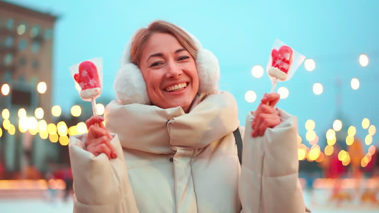 Joyful woman in earmuffs covering eyes with Christmas candies