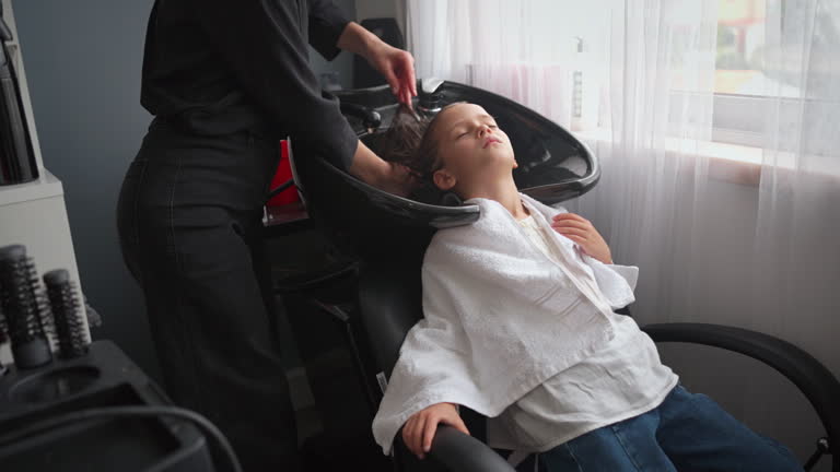 Relaxed girl having her hair washed by female hairdresser in salon