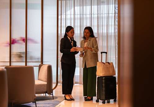 The concierge welcomes the business traveler and uses her portable device to discuss the services of the facilities.