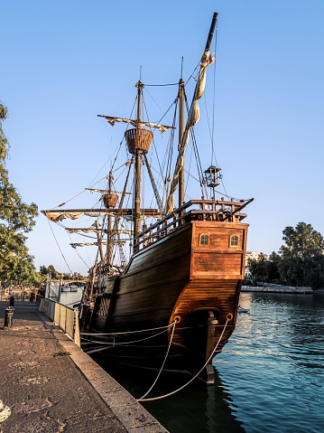 The Nao Victoria replica carrack ship docked at the Guadalquivir River in the historic central downtown area of Seville, Spain, sunset golden hour
