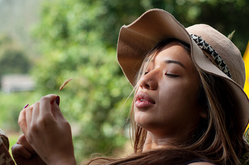 beautiful young woman in hat enjoying the delicate touch of nature while enjoying a moment of mental relaxation