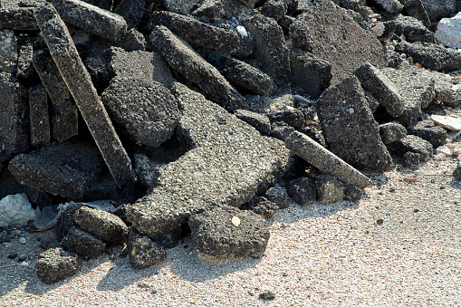Cracked asphalt pieces after demolition of a road surface in a construction site for renovation ready to be recycled.