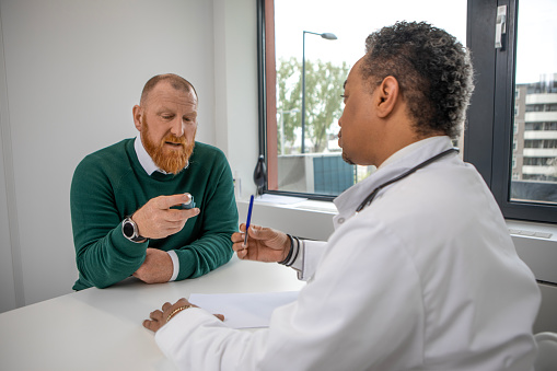 Medical check-up for asthmatic redhead man and diverse doctor