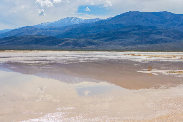 Bad water basin in Death Valley national park, the lowest elevation in North America. At 282 feet below sea level another world landscape can be found. Visitors walk across the area next to salty water and mineral deposits in the stark but beautiful landscape.