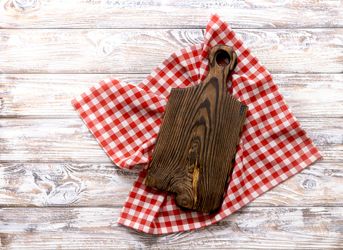 Cutting chopping brown wooden board decorated with red picnic checkered cloth top view. Empty timber,plank. Dish plate advertisement design.Tray.