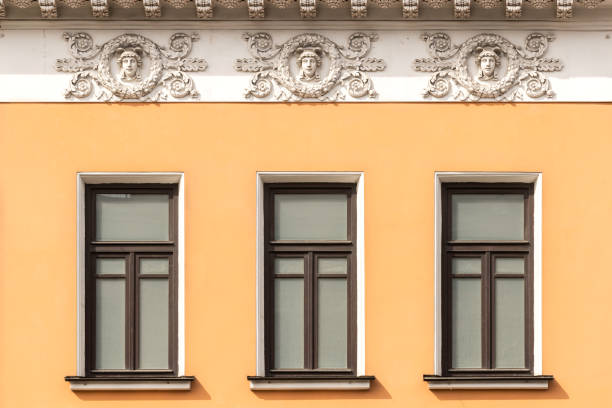 istock Three classic window frames on an orange building facade with medallion reliefs above them. 2149393199