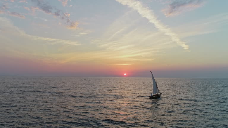 Aerial View of a Man Sailing a Vintage Sailboat Alone on the Sea at Sunset. Concept of Freedom, Travel, Vastness, Loneliness, Timelessness, Exploration, Solitude, Adventure, Serenity, Medieval Boat