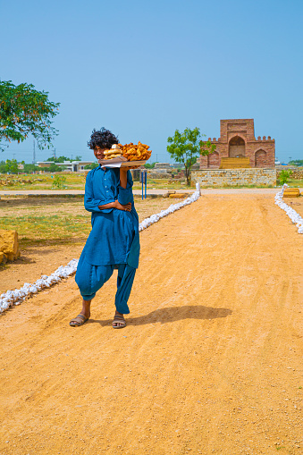 24 September 2023, Thatta, Pakistan. Younge man sells food in Makli Necropolis graveyard in Thatta, Pakistan.