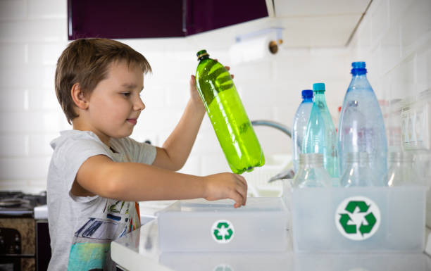 istock A boy enthusiastically puts plastic bottles into boxes separately from caps for recycling. Sorting plastic waste for recycling. The boy cares about preserving nature by sending plastic for recycling. 2149397476