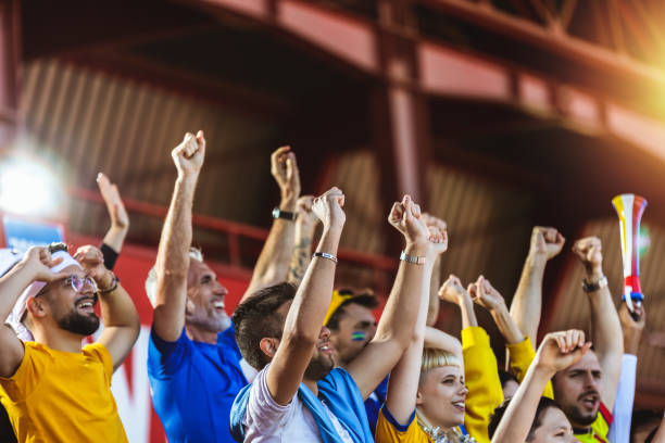 Sport fans cheering at the game on stadium.
