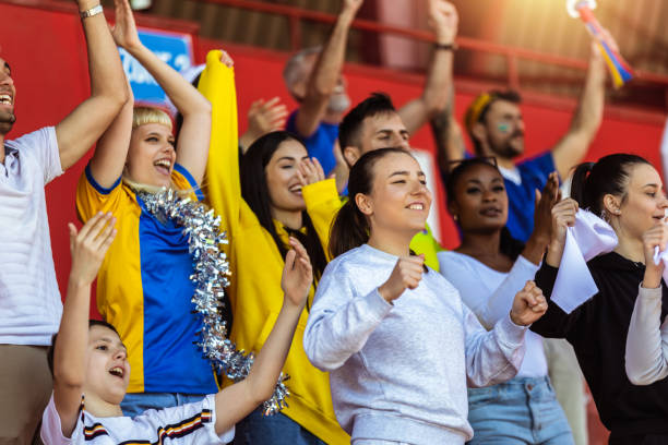 Sport fans cheering at the game on stadium.