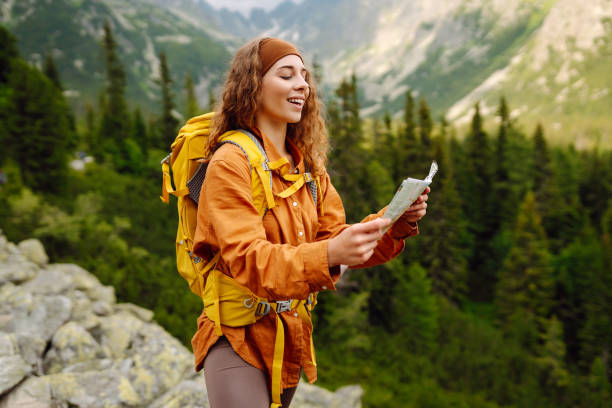 istock Stylish woman looking at map, exploring woods and mountains. 2149404735