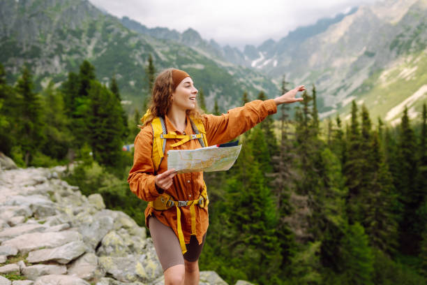 istock Stylish woman looking at map, exploring woods and mountains. 2149404739