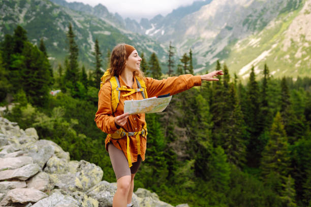 istock Stylish woman looking at map, exploring woods and mountains. 2149404741